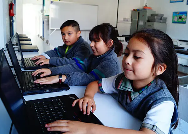 alumnos de primaria particular privada en Cuautitlán Izcalli utilizando computadoras portátiles, desarrollando habilidades digitales
