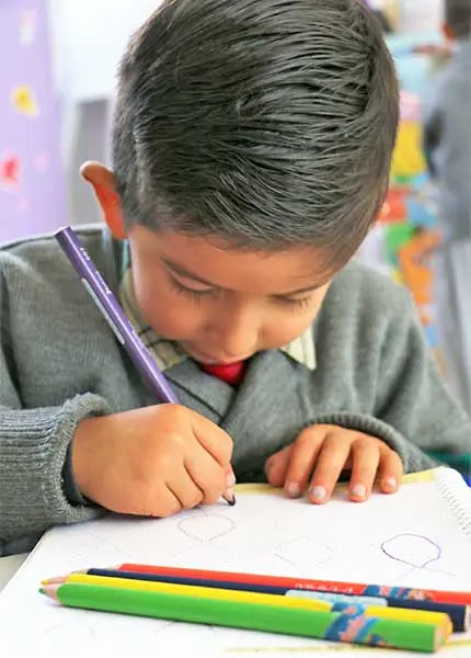 Niño en jardín de niños aprendiendo con lápiz y cuaderno con enfoque académico