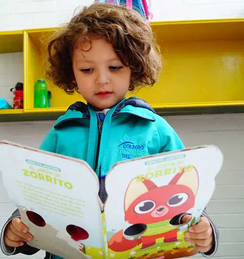 Alumno pequeño leyendo un cuento en jardín de niños privado